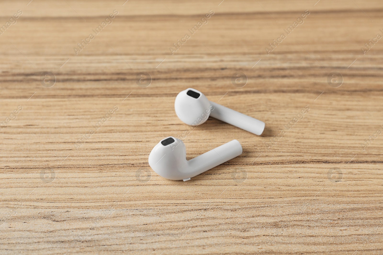 Photo of Pair of modern wireless earphones on wooden table