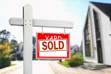 Image of Yard sale sign with Sold sticker near house