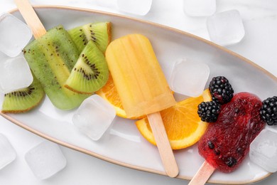 Photo of Plate of delicious popsicles, ice cubes and fresh fruits on white background, top view