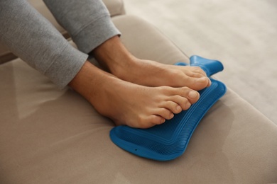 Man warming feet with hot water bottle on sofa, closeup