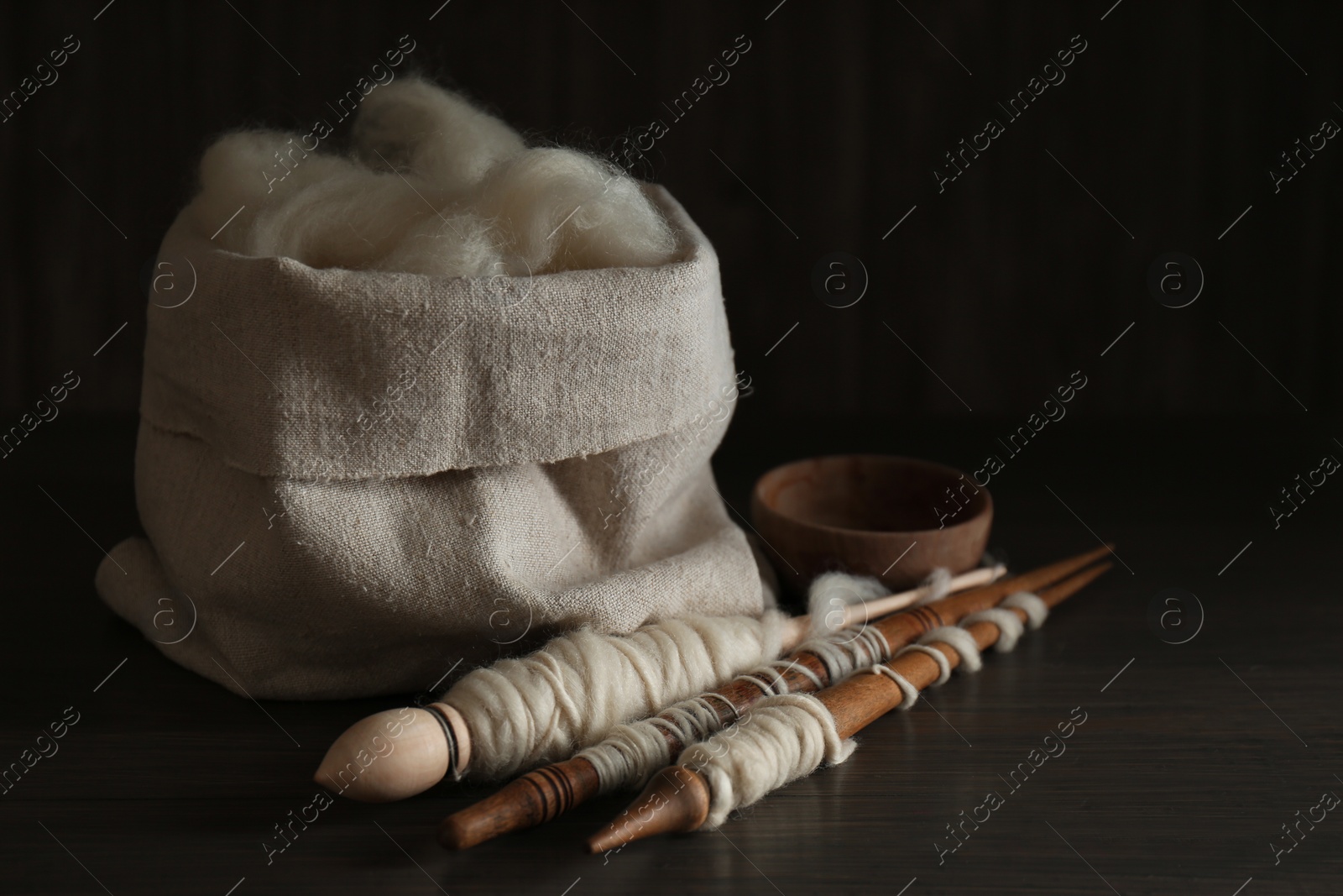 Photo of Soft white wool and spindles on wooden table