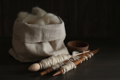 Soft white wool and spindles on wooden table