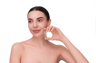 Beautiful young woman holding skincare ampoule on white background