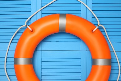 Photo of Orange lifebuoy on turquoise wooden background. Rescue equipment