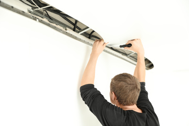 Repairman installing white stretch ceiling in room