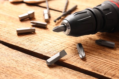 Photo of Electric screwdriver with bit set on wooden table, closeup