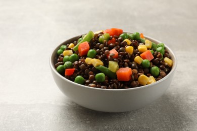 Photo of Delicious lentils with vegetables in bowl on light grey table, closeup
