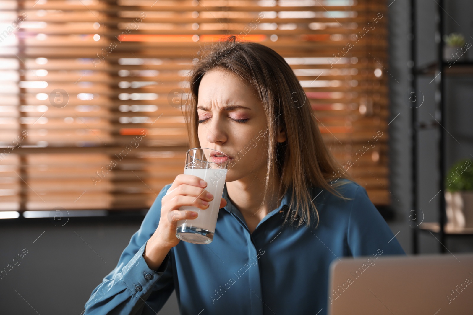 Photo of Woman taking medicine for hangover in office