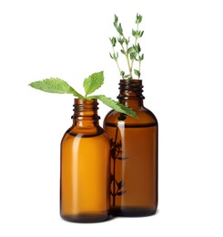 Photo of Bottles of essential oil with mint and thyme isolated on white