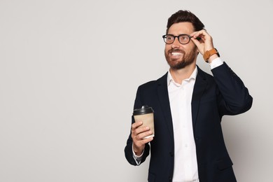 Photo of Handsome bearded man with glasses and paper cup on light grey background. Space for text