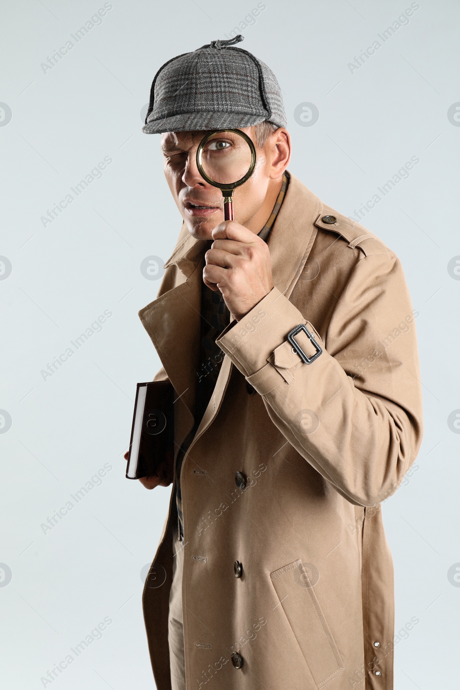 Photo of Male detective looking through magnifying glass on grey background