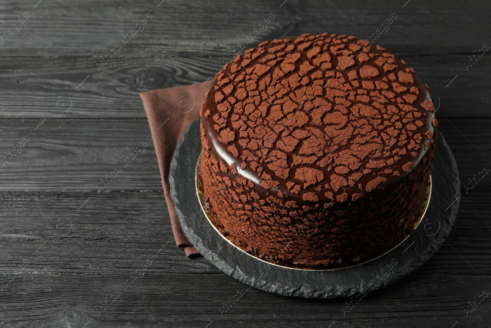 Photo of Delicious chocolate truffle cake on black wooden table, space for text