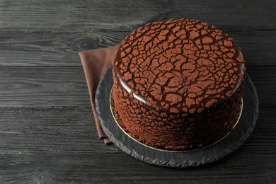 Delicious chocolate truffle cake on black wooden table, space for text