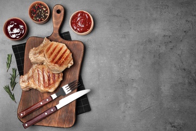 Flat lay composition with grilled meat on grey background. Space for text