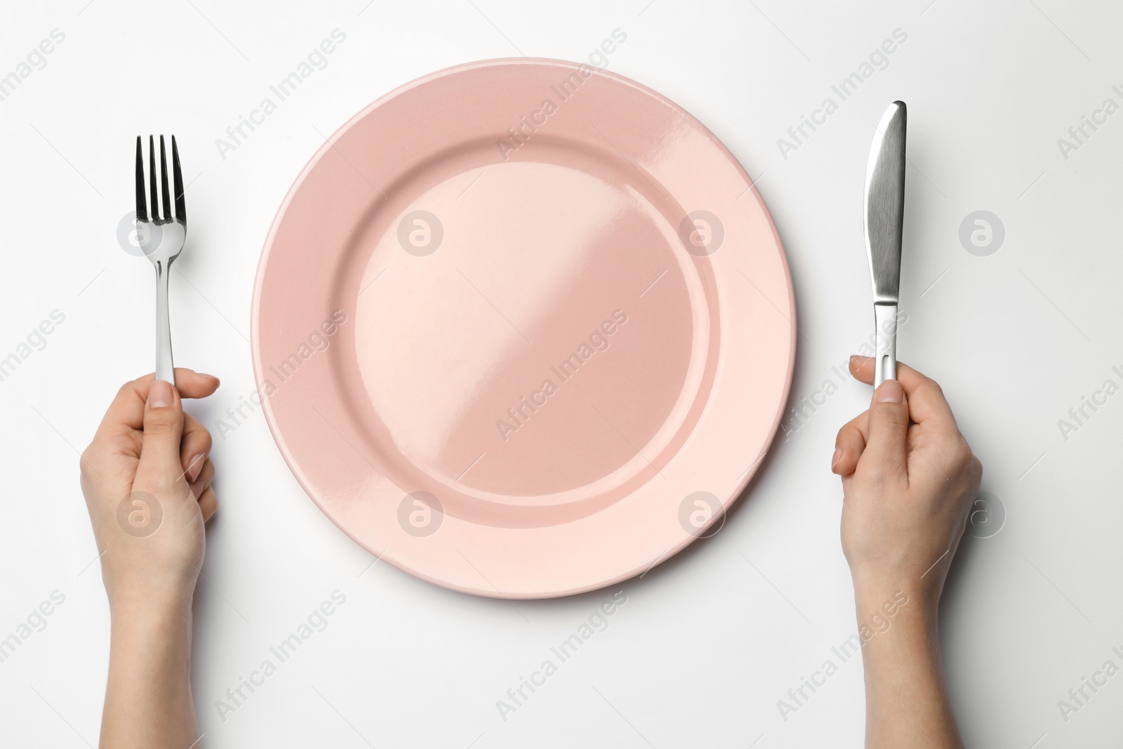 Photo of Woman with fork, knife and empty plate on white background, top view