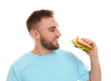 Young man eating tasty sandwich on white background