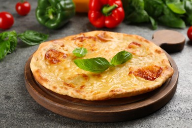 Delicious khachapuri with cheese and basil on grey table, closeup