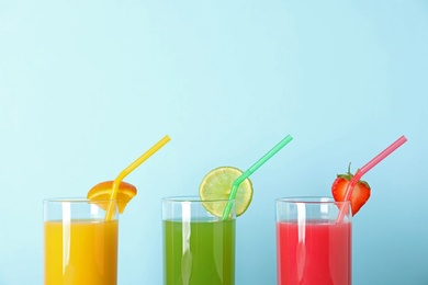 Photo of Three glasses with different juices and straws on color background