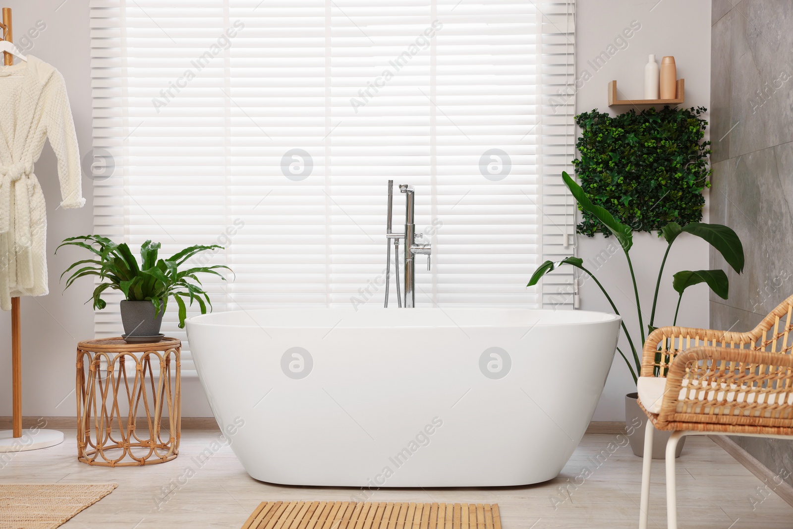 Photo of Green artificial plants and white tub in bathroom