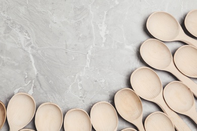 Many wooden spoons on grey marble table, flat lay with space for text. Cooking utensils