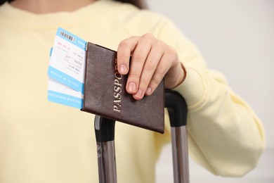 Photo of Tourist with suitcase, passport and tickets on blurred background, closeup