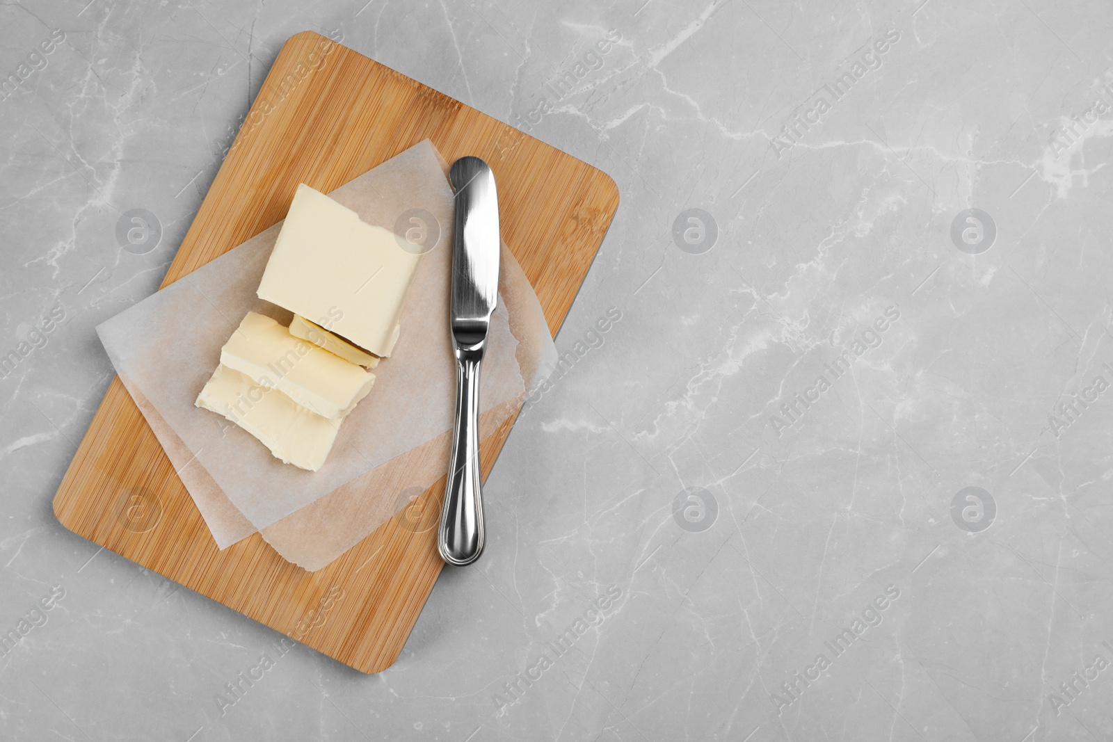 Photo of Wooden board with tasty fresh butter and knife on table, top view