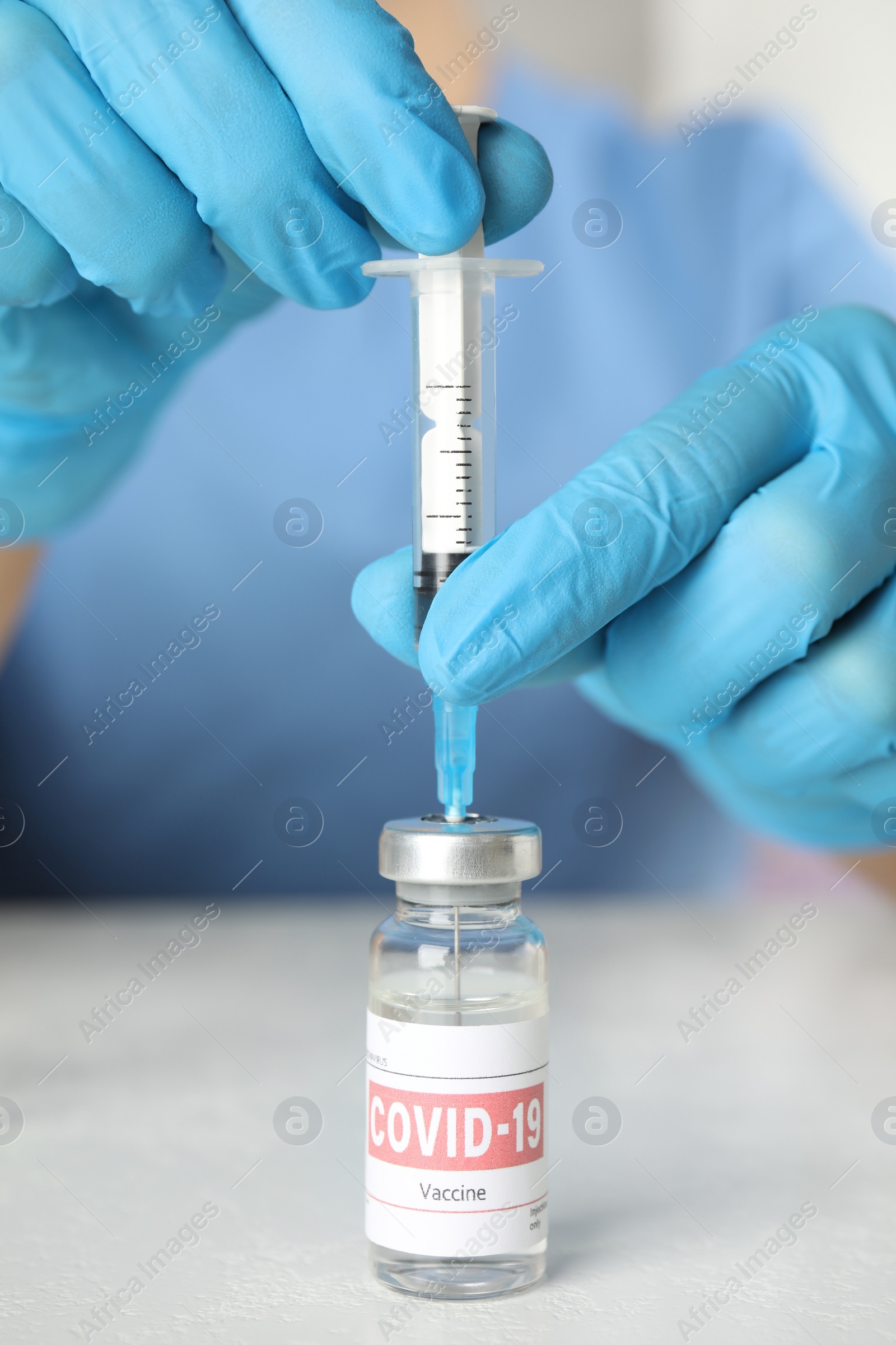 Photo of Doctor filling syringe with coronavirus vaccine at table in laboratory, closeup