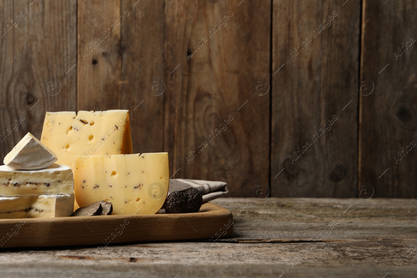 Photo of Different types of cheese and truffles on wooden table, space for text