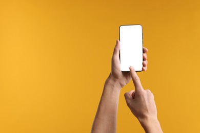 Photo of Man using smartphone with blank screen on yellow background, closeup. Mockup for design