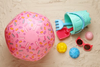 Photo of Pink inflatable ball, sunglasses and plastic beach toys on sand, flat lay