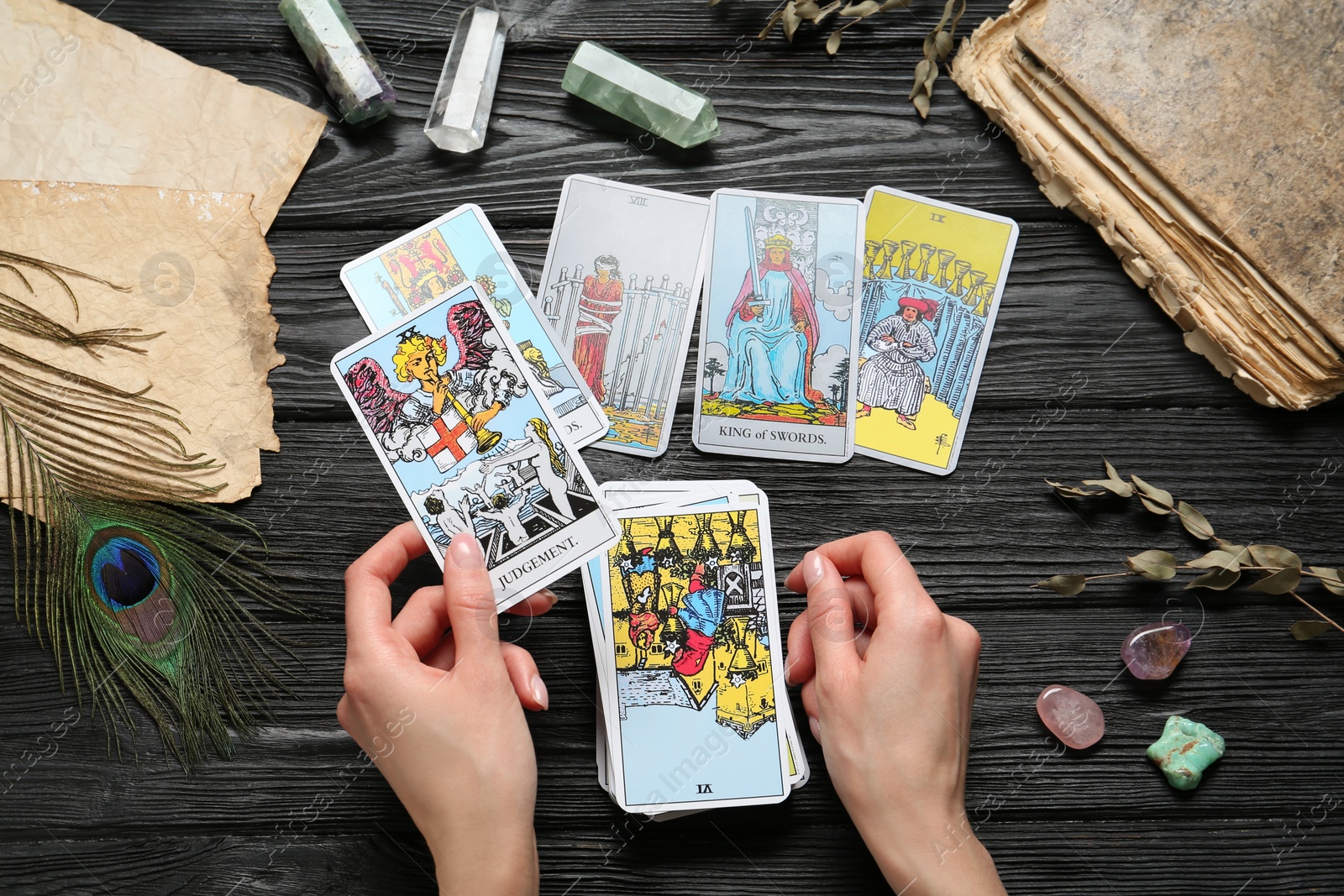 Photo of Woman with tarot cards at black wooden table, top view