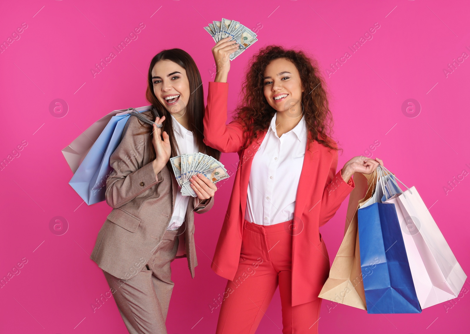 Photo of Young women with money and shopping bags on color background