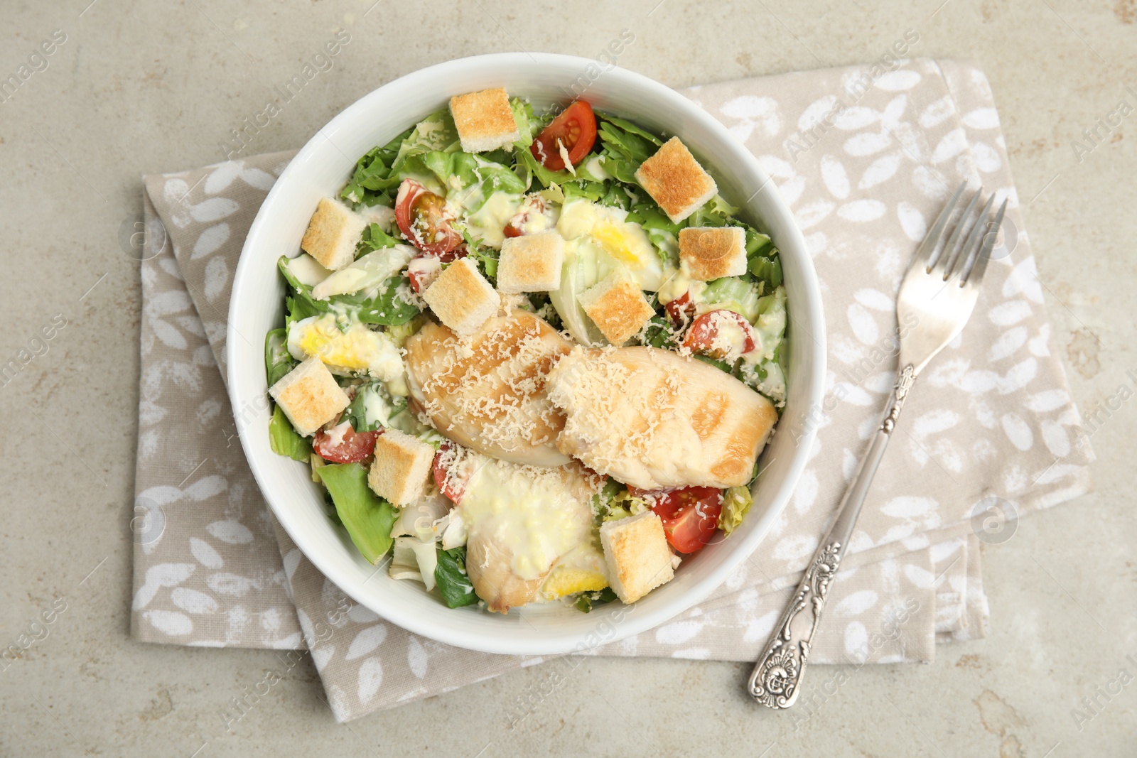 Photo of Delicious fresh Caesar salad in bowl on light grey table, top view