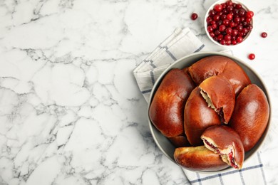 Photo of Delicious baked cranberry pirozhki in bowl on white marble table, flat lay. Space for text