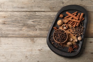 Photo of Different spices and nuts on wooden table, top view. Space for text