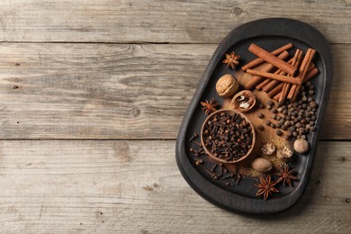 Different spices and nuts on wooden table, top view. Space for text