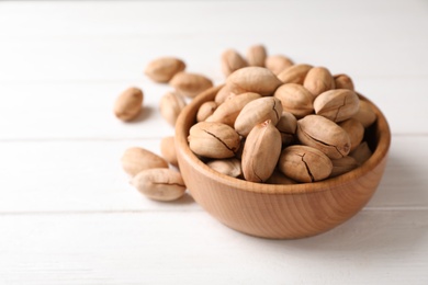 Photo of Pecan nuts in bowl on wooden table. Space for text