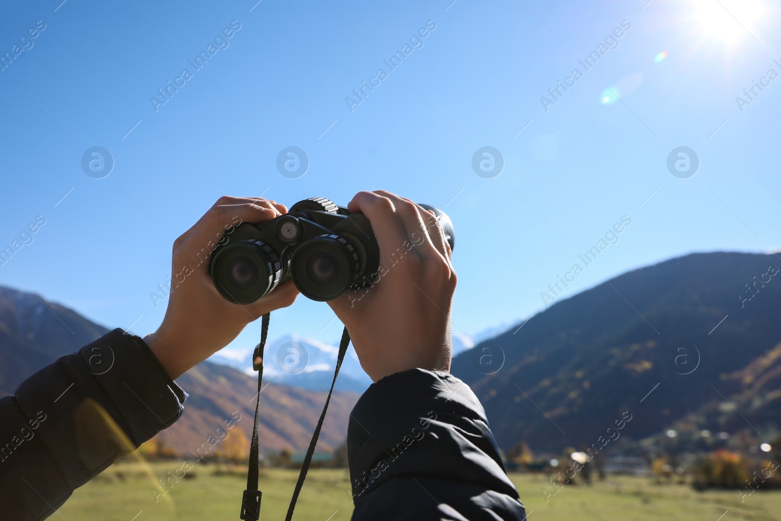 Photo of Boy holding binoculars in beautiful mountains on sunny day, closeup