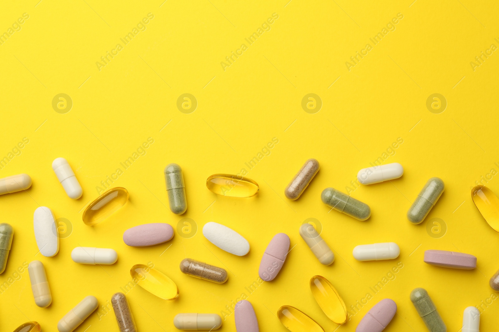 Photo of Different vitamin pills on yellow background, flat lay. Space for text