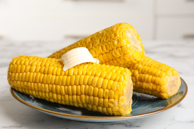 Delicious boiled corn with butter on white marble table, closeup