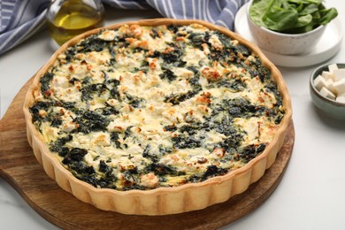 Delicious homemade spinach quiche on white table, closeup