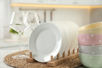 Photo of Clean plates, bowls and glasses on table in kitchen