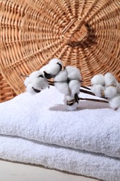 Photo of Stacked terry towels and cotton branches on white table