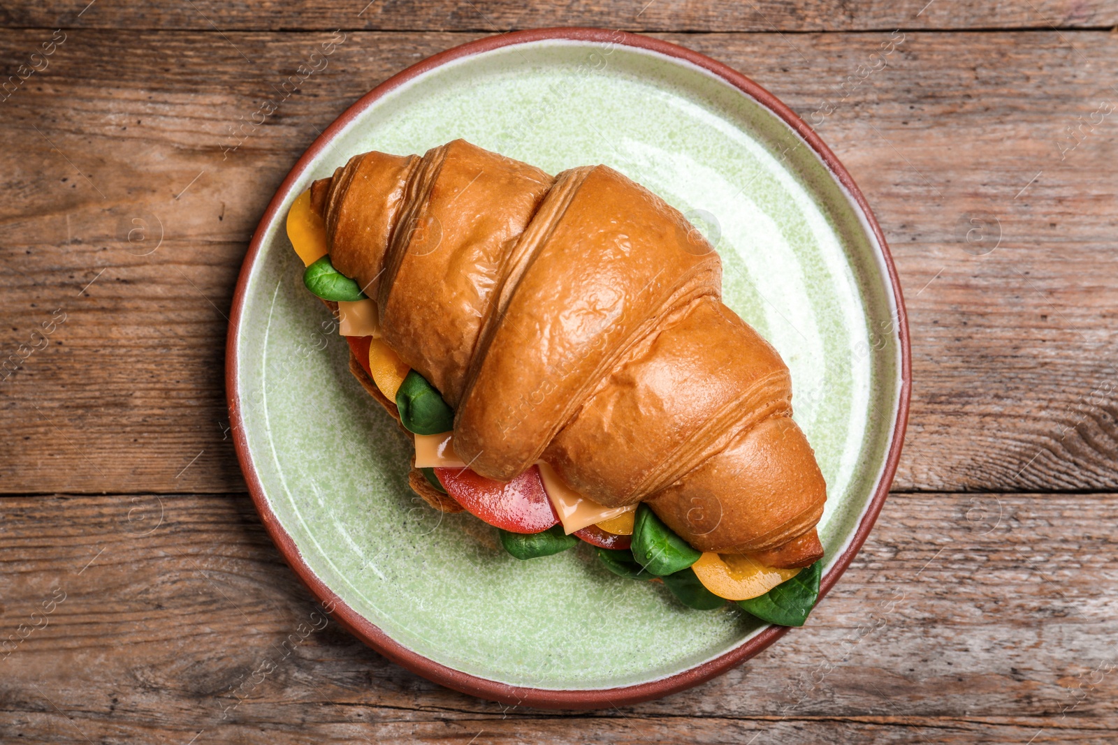 Photo of Tasty croissant sandwich on wooden table, top view