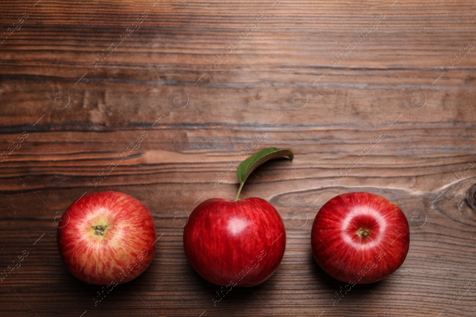 Photo of Ripe red apples on wooden table, flat lay. Space for text