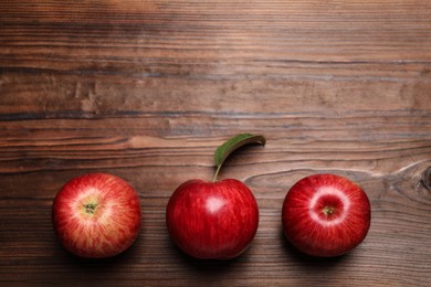 Photo of Ripe red apples on wooden table, flat lay. Space for text