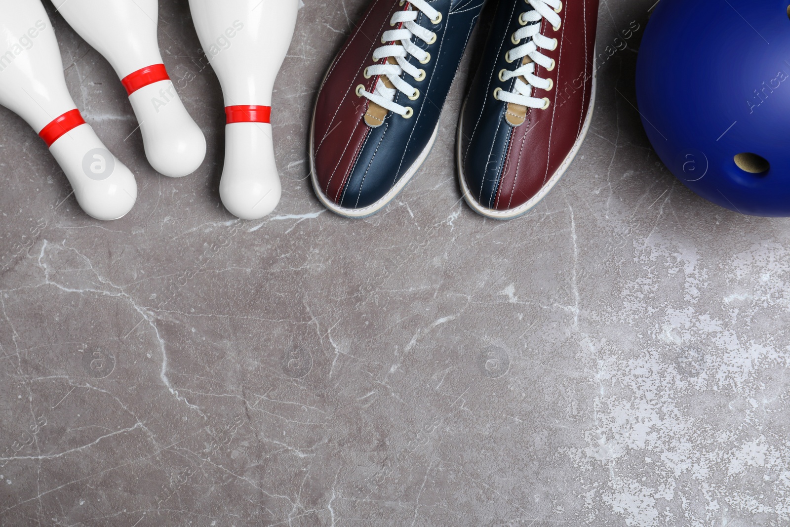 Photo of Bowling shoes, pins and ball on grey marble table, flat lay. Space for text