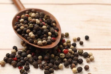 Photo of Aromatic spices. Different peppers in spoon on wooden table, closeup