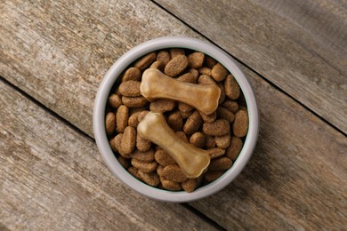 Dry dog food and treats (chew bones) on wooden floor, top view