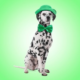 Image of St. Patrick's day celebration. Cute Dalmatian dog with leprechaun hat and bow tie on green background